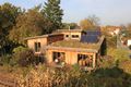 Holzhaus mit Dachbegrünung (Außenwand aus unbehandeltem Lärchenholz in Ständerbauweise, Wärmedämmung aus eingeblasenen Hobelspänen, Innenwände aus Lehmputz auf Schilfrohrplatten; Heizung und Warmwasserbereitung durch Grundofen und Sonnenkollektoren; weitgehend in Eigenleistung durch <!--LINK'" 0:64--> erbaut.)