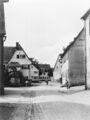 Blick in die kopfsteingepflasterte <a class="mw-selflink selflink">Brückenstraße</a> mit Kriegerdenkmal und Gebäude dahinter <!--LINK'" 0:71--> und 2, Gebäude rechts <!--LINK'" 0:72--> und 1 dahinter, im Hintergrund <!--LINK'" 0:73-->, 1936