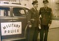 Zwei Stadtpolizisten vor einem Streifenwagen der amerikanischen Militärpolizei (1949).