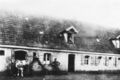 das alte, 1958 abgerissene Bauernhaus heute <!--LINK'" 0:123--> mit Besitzer Friedrich Schneider, Ehefrau Maria Appolonia und oben am Fenster Tochter Kätha, Aufnahme von 1910